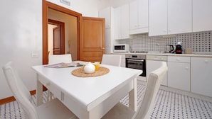A compact kitchen with white cabinets, a microwave, an oven, and a coffee maker. - Exclusive Historic Ghetto Flatinrome (ROMA)
