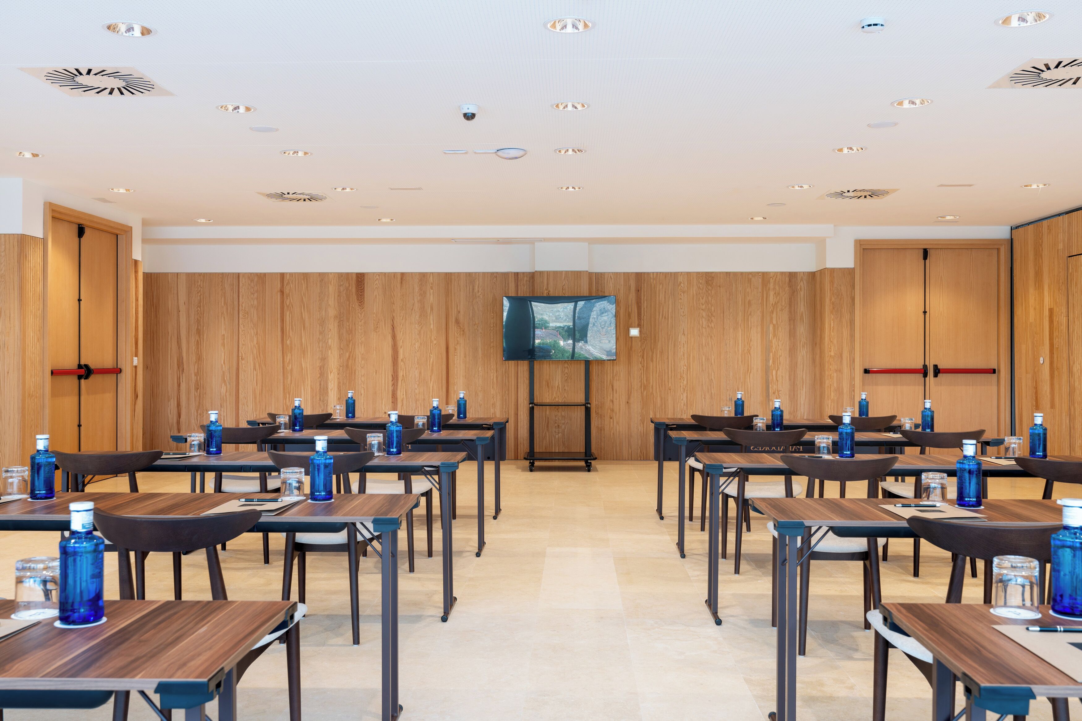 A conference room with wooden panel walls, a large flat-screen TV, and tables arranged for meetings.