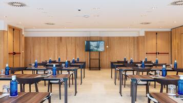 A conference room with wooden panel walls, a large flat-screen TV, and tables arranged for meetings.