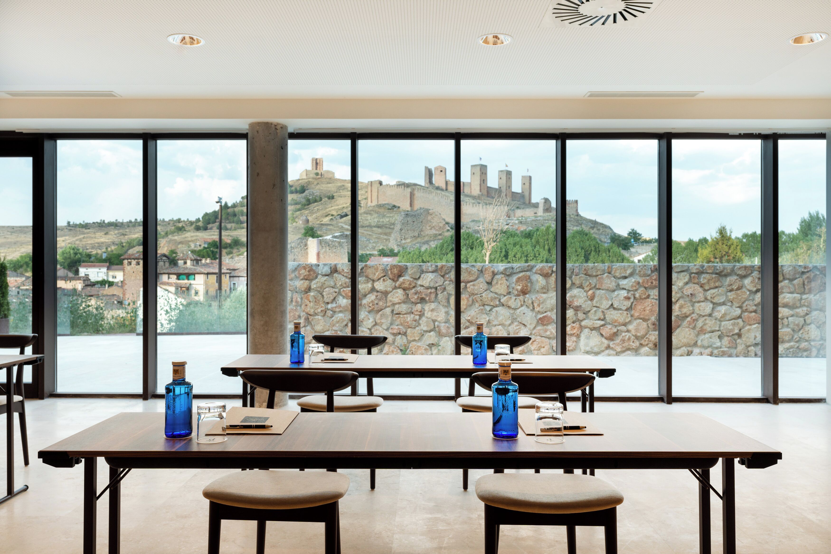 A dining area with large windows offering a view of a historic castle on a hill.