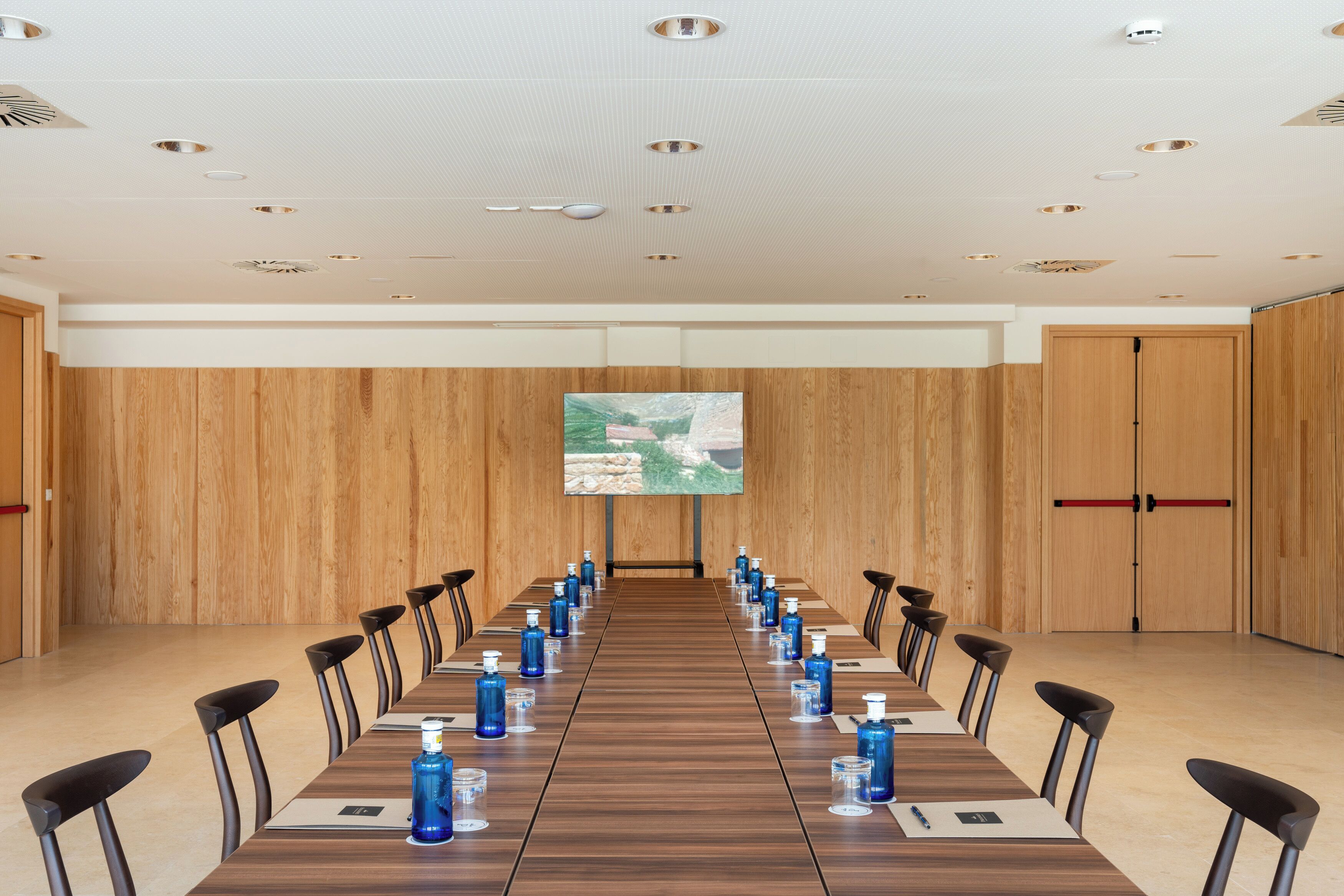 A conference room with a long table, chairs, and a screen at the front.