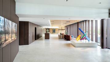 A modern lobby with a long corridor, a reception desk, and a colorful sculpture.