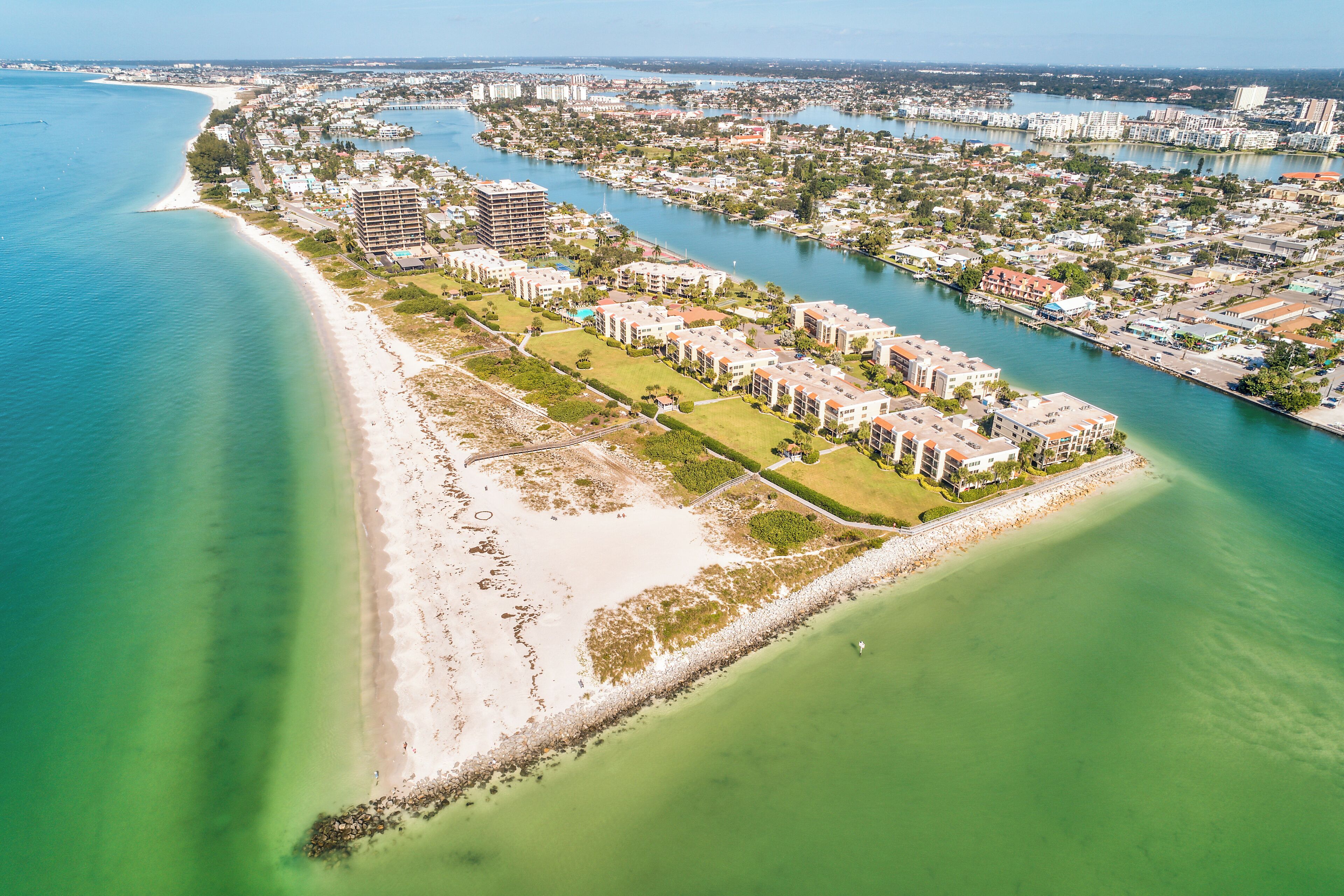 Vista aérea de un complejo turístico costero con propiedades frente a la playa, un puerto deportivo y un gran hotel.