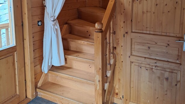 A wooden staircase with a white curtain, a wooden door, and a tiled floor. - Chalet Briançon Serre Chevalier (Briançon)