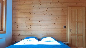 A room with a bed, wooden walls, and a door. - Chalet Briançon Serre Chevalier (Briançon)