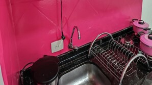 Una cocina con pared rosa, un fregadero, un escurreplatos y un microondas.