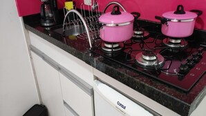 Una cocina con un horno rosa, un lavavajillas blanco y un tapete rojo en el suelo.