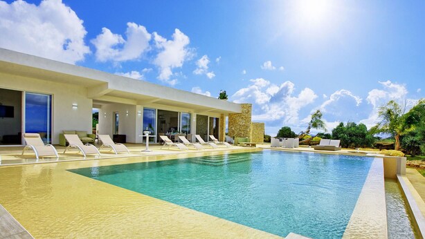A modern pool area with lounge chairs and a stone wall.