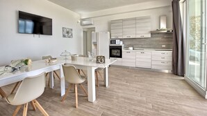 A modern kitchen with a dining area, featuring a TV, a large flower arrangement, and a dining table with chairs.