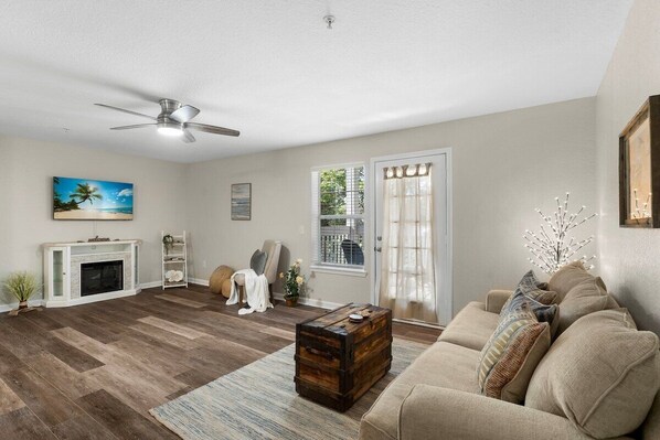 A living room with a fireplace, a ceiling fan, a sofa, and a coffee table.