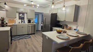 A modern kitchen with white cabinetry, a central island with bar stools, and pendant lighting.