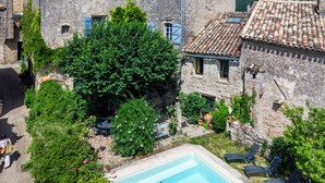 A stone building with a swimming pool, surrounded by greenery. - Auberge des Hirondelles (Puycelci)