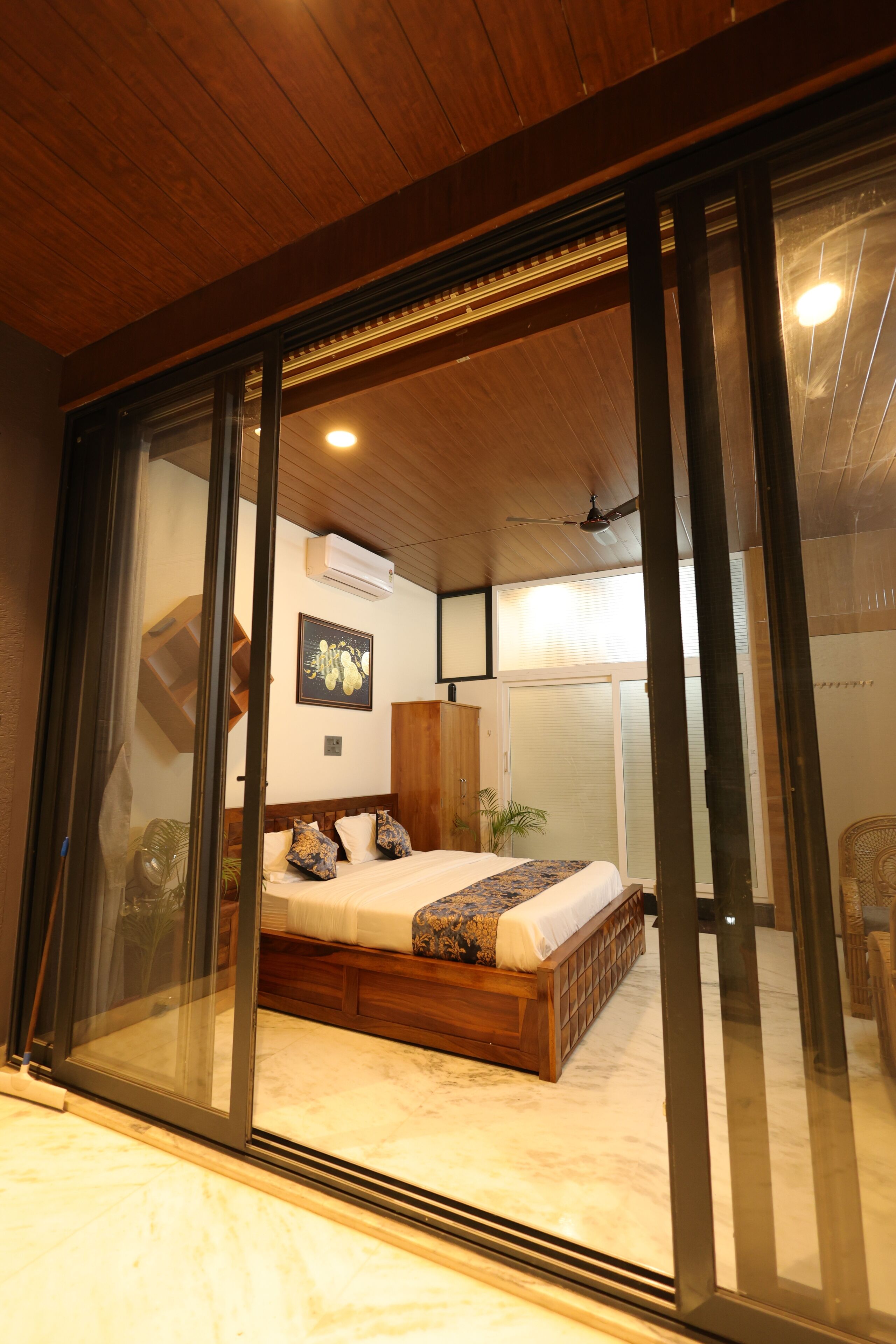 Un dormitorio con techo de madera, una cama con colcha estampada y un ventanal con persianas.
