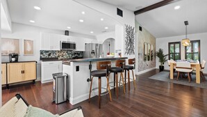 A modern kitchen with white cabinets, stainless steel appliances, and a bar area with stools. - Heated Pool | Game Room | Arcade | Sleeps14 | BBQ (Bradenton)