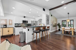 A modern kitchen with white cabinets, stainless steel appliances, and a bar area with stools. - Heated Pool | Game Room | Arcade | Sleeps14 | BBQ (Bradenton)