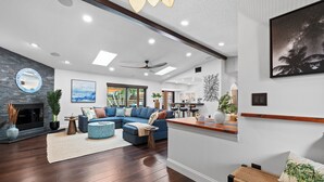 A spacious living room with a sectional sofa, a fireplace, and a view of the outdoors. - Heated Pool | Game Room | Arcade | Sleeps14 | BBQ (Bradenton)