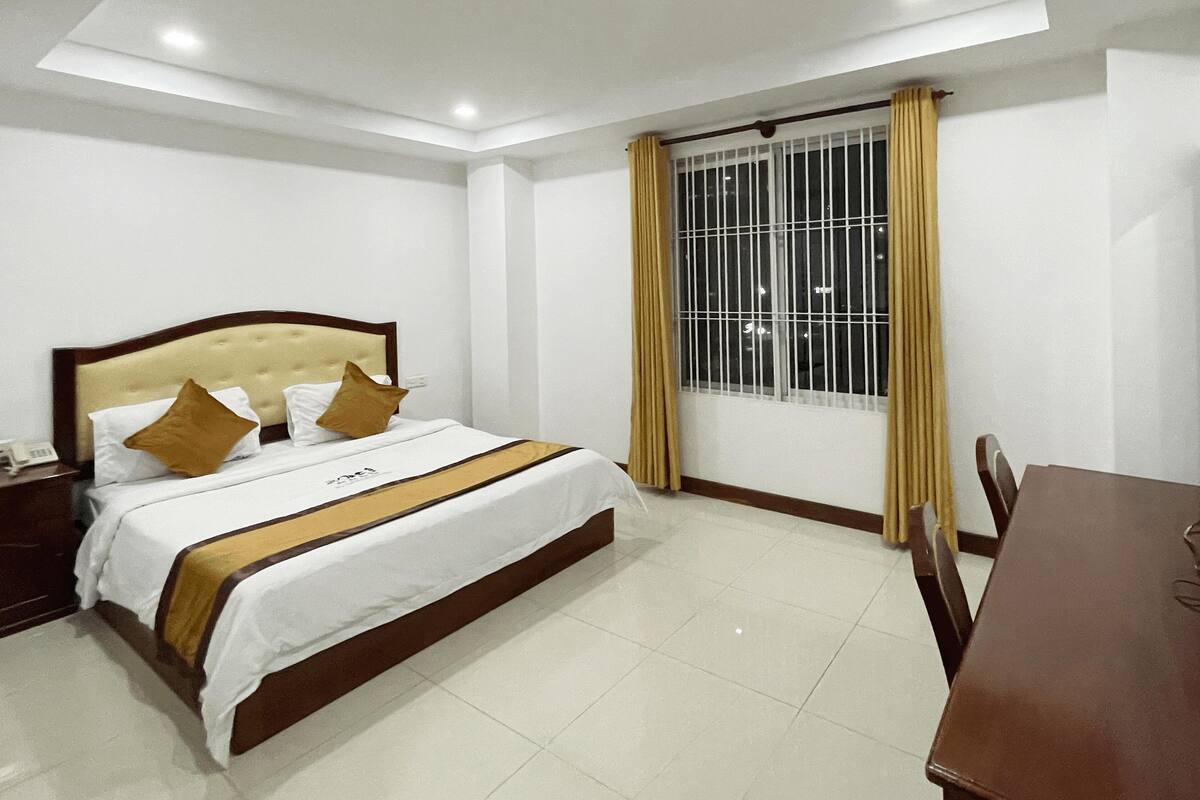 A hotel room with a bed, a desk, and a television.