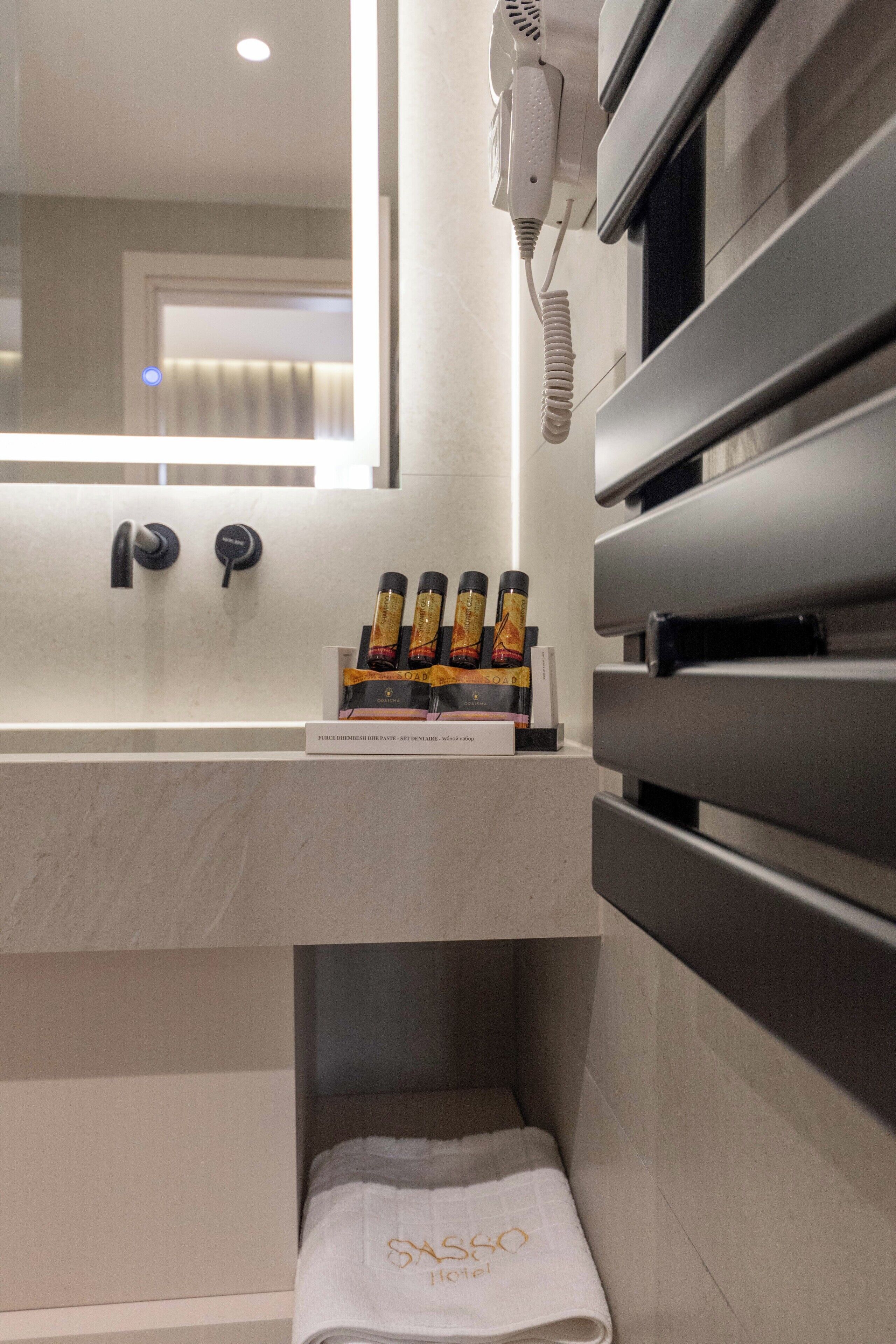 Un baño moderno con un espejo grande, un secador de pelo y un perchero para toallas.