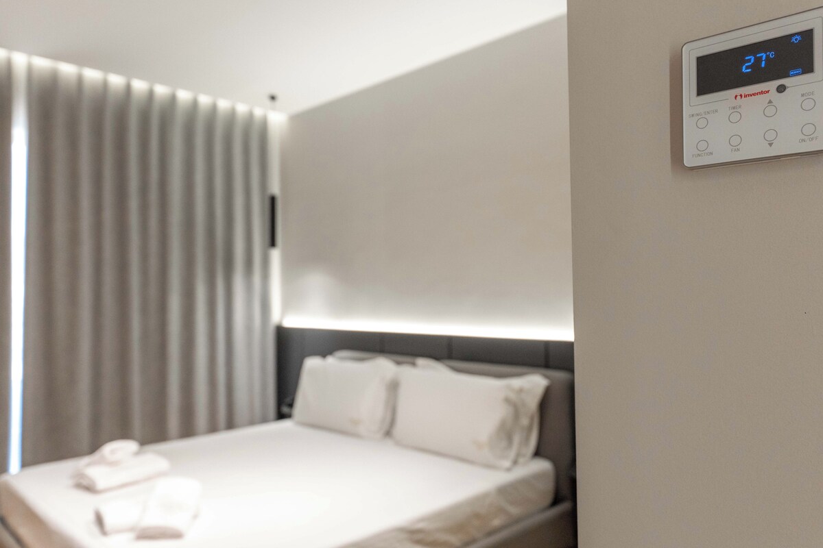 Une chambre d’hôtel avec un lit, un panneau de commande et une fenêtre avec des stores.