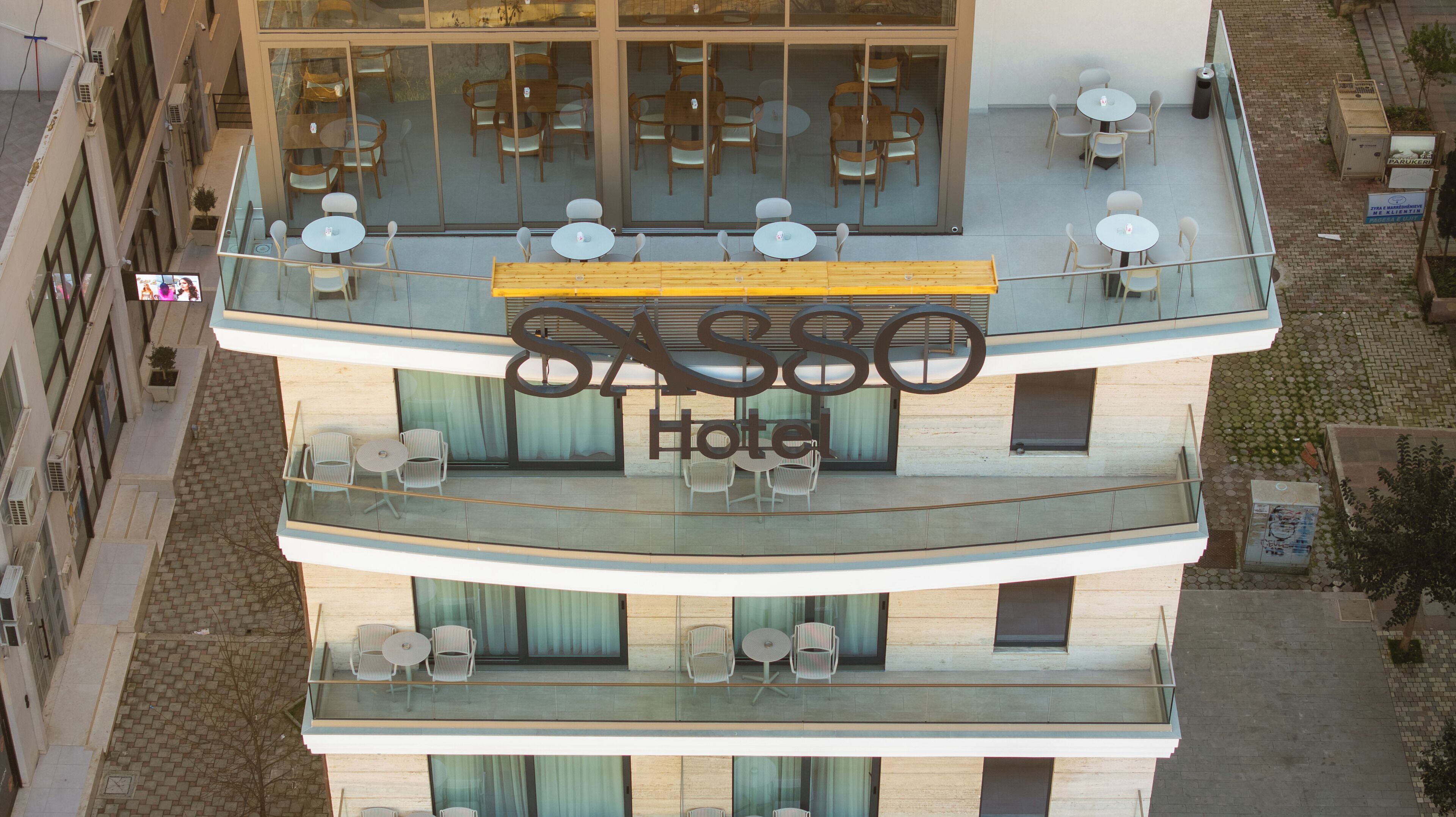 Un hotel con terraza en la azotea que ofrece asientos al aire libre y un letrero grande.