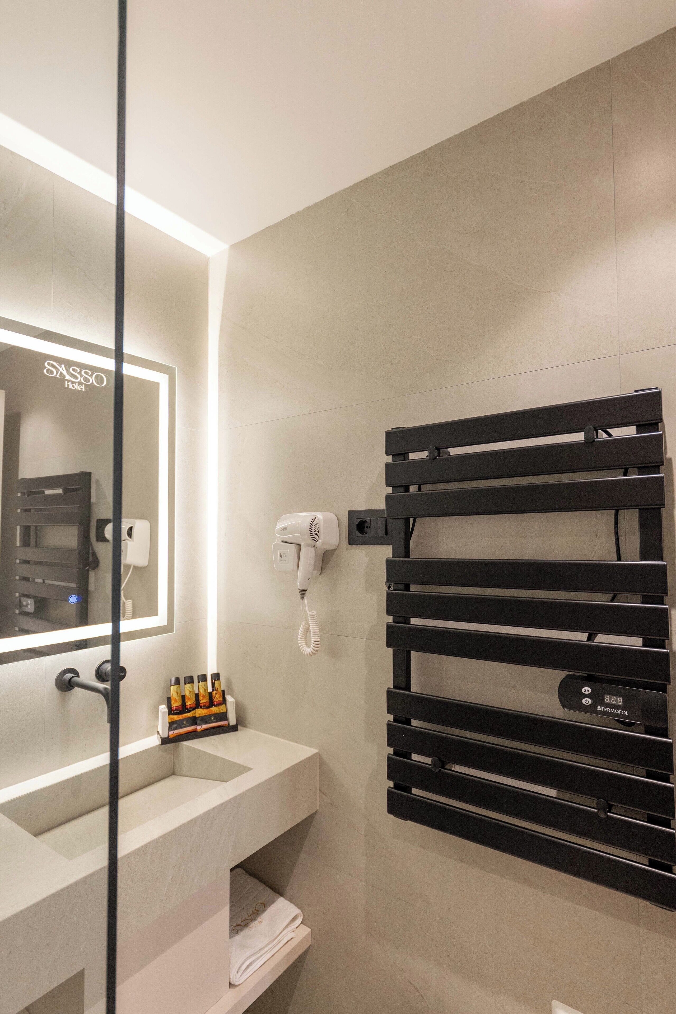 Un baño moderno con espejo, secador de pelo y toallero.