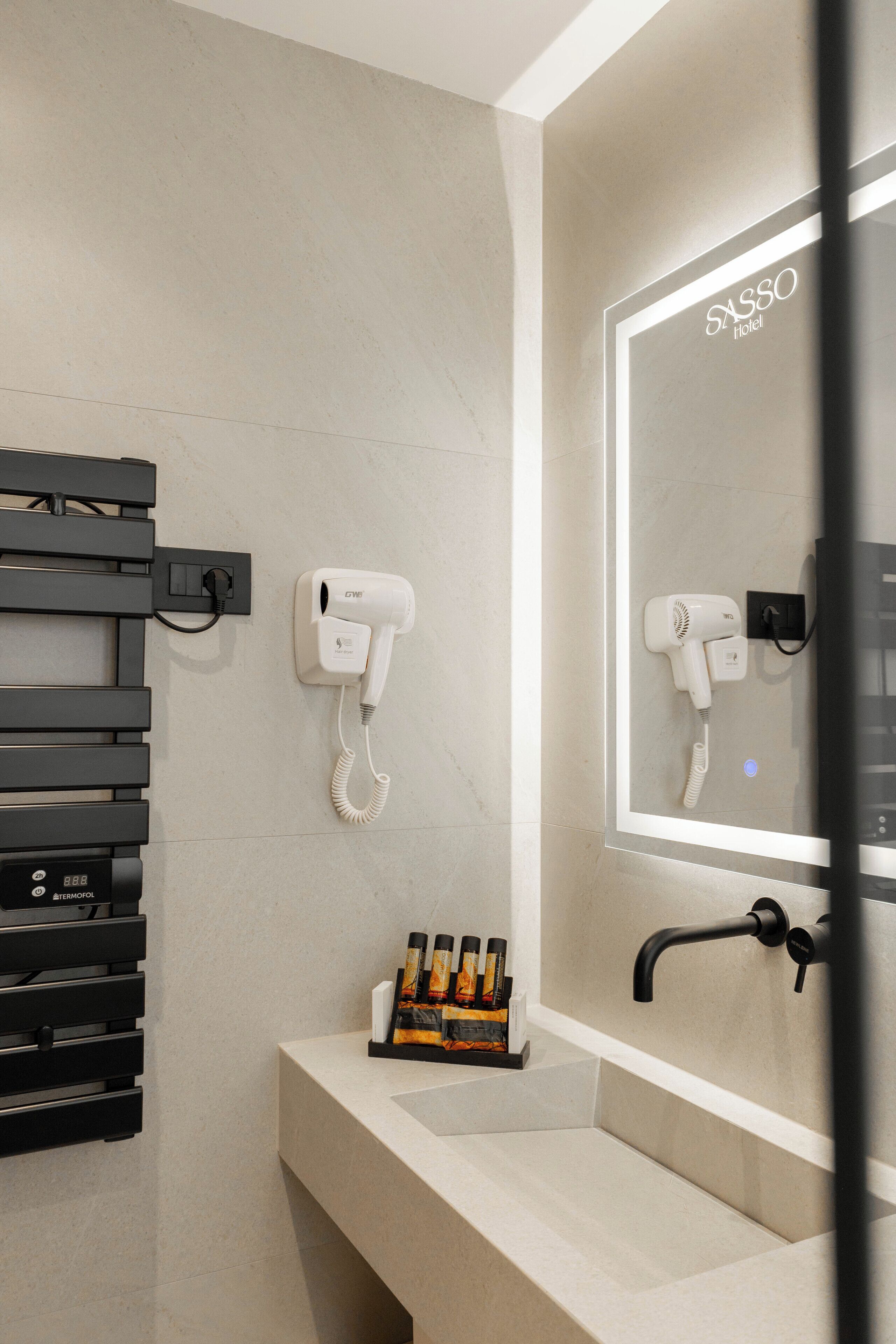 Een moderne badkamer met een haardroger, spiegel en handdoekrek.