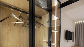 A modern room with a wooden wardrobe, a built-in TV, and a desk. - Sasso Hotel (Vlorë)