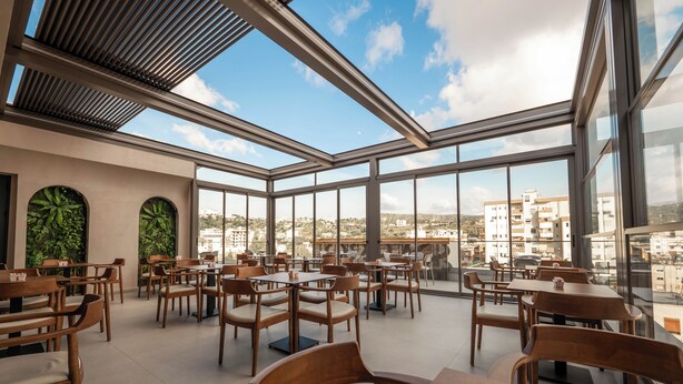 A spacious rooftop restaurant with large windows offering city views. - Sasso Hotel (Vlorë)