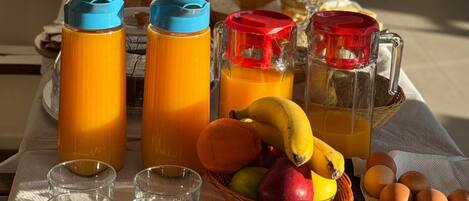 A breakfast table with orange juice, a fruit basket, and eggs.