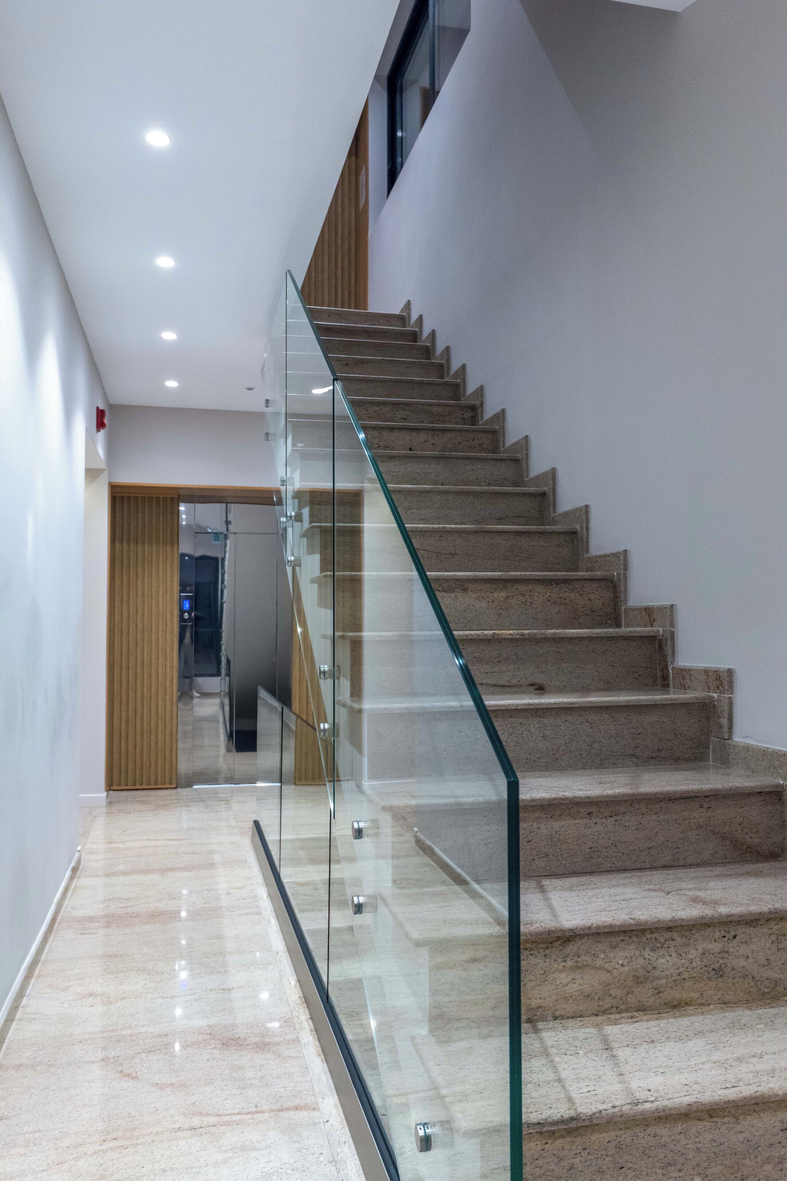 A modern staircase with glass railings and a polished marble floor.