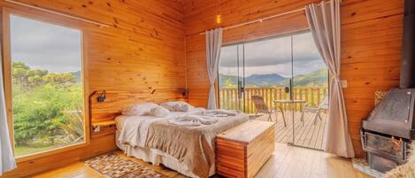 Un dormitorio de cabaña de madera con cama, banco y chimenea.
