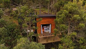 A cabin with a wooden deck and a glass door leading to a bedroom. - Cascata dos Amores (Urubici)