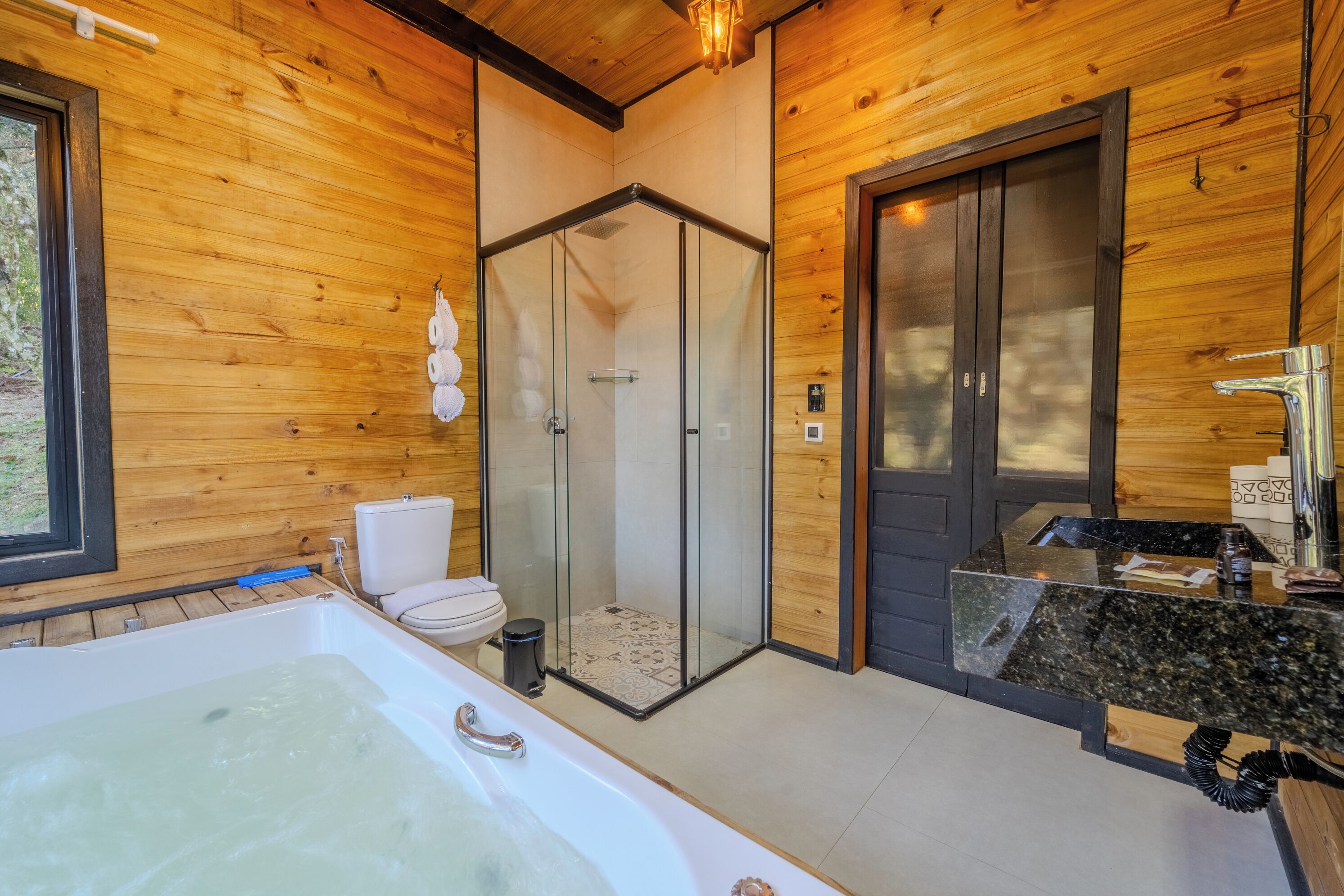 Un baño moderno con ducha envuelta en vidrio, una bañera grande y un tocador con encimera de granito.