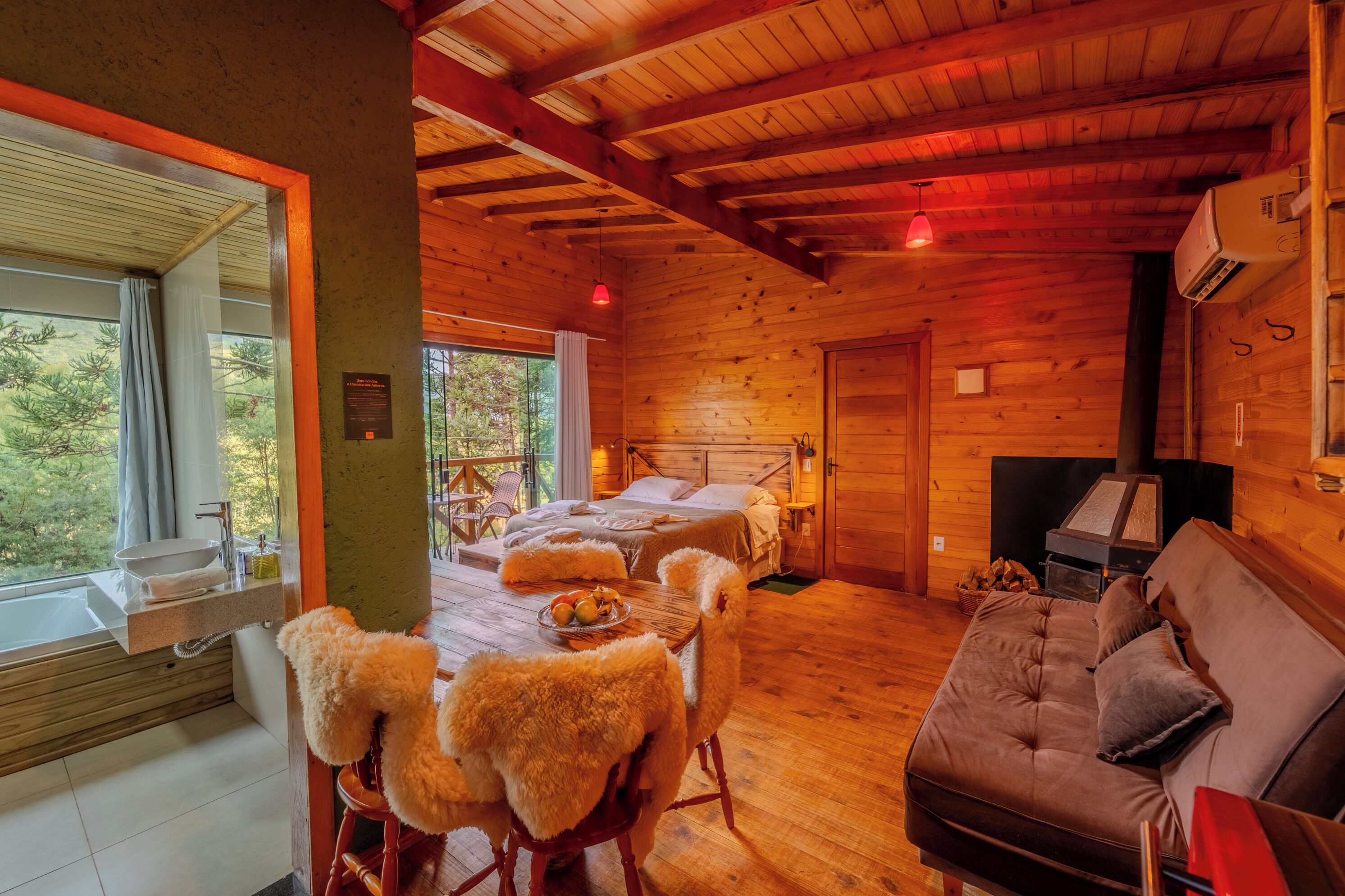 A cozy cabin with a wooden interior, a large bed, a sofa, and a dining area with a table and chairs.
