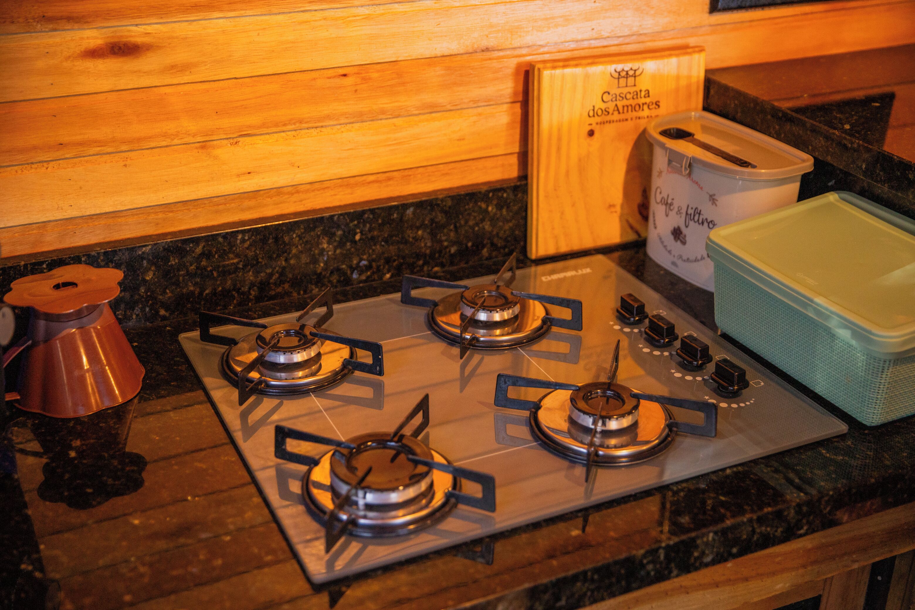 A kitchen with a gas stove, a wooden cutting board, and a coffee maker.