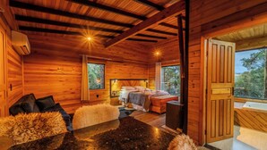 A wooden cabin interior with a dining area, a bedroom with a bed and a window, and a bathroom with a bathtub. - Cascata dos Amores (Urubici)