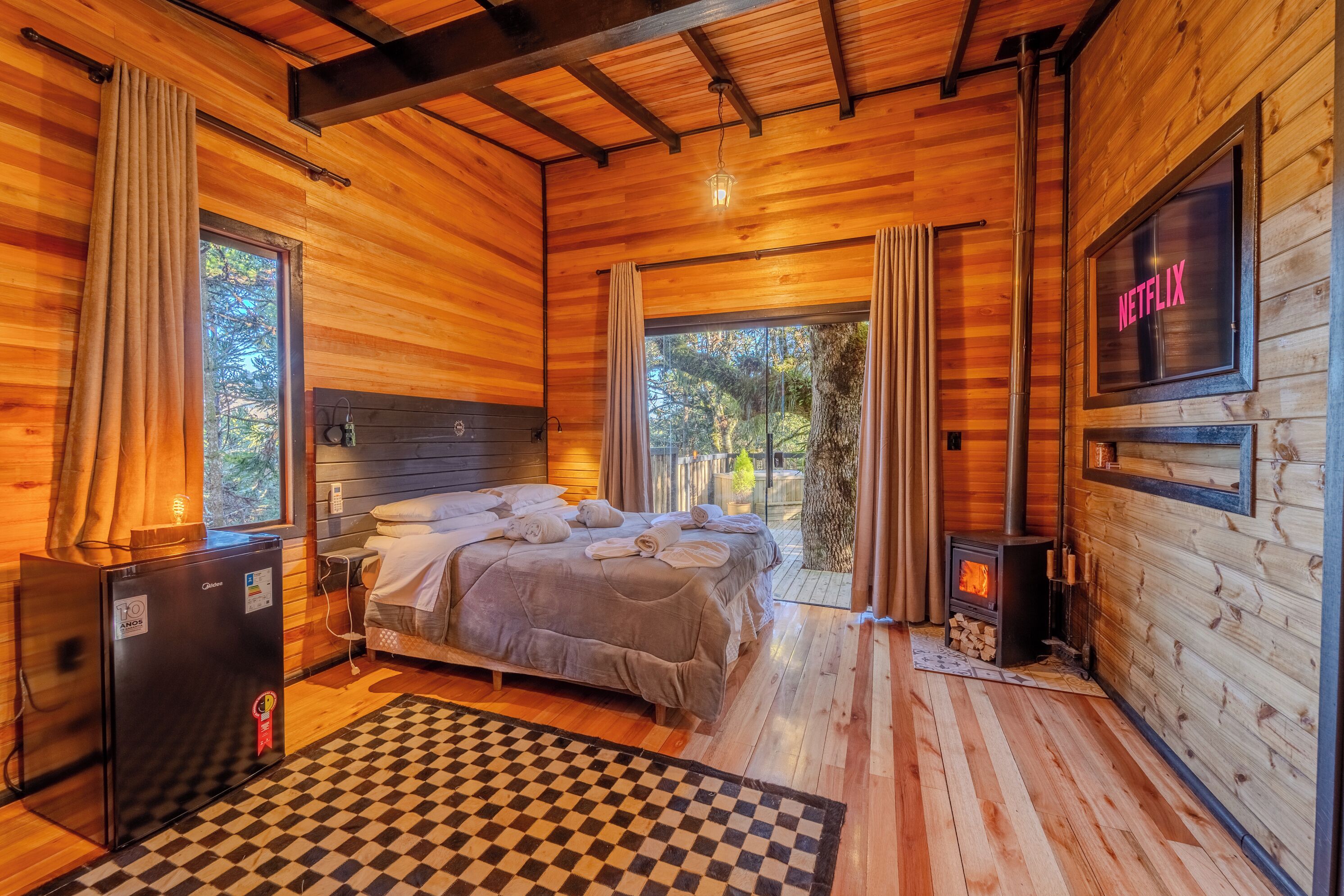 Una habitación de cabaña de madera acogedora, con cama, televisión y chimenea.