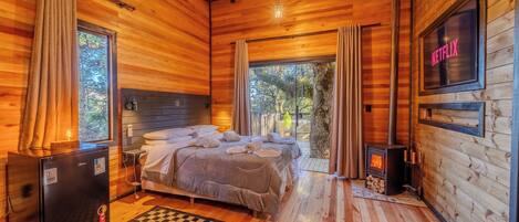 Una habitación de cabaña de madera acogedora, con cama, televisión y chimenea.