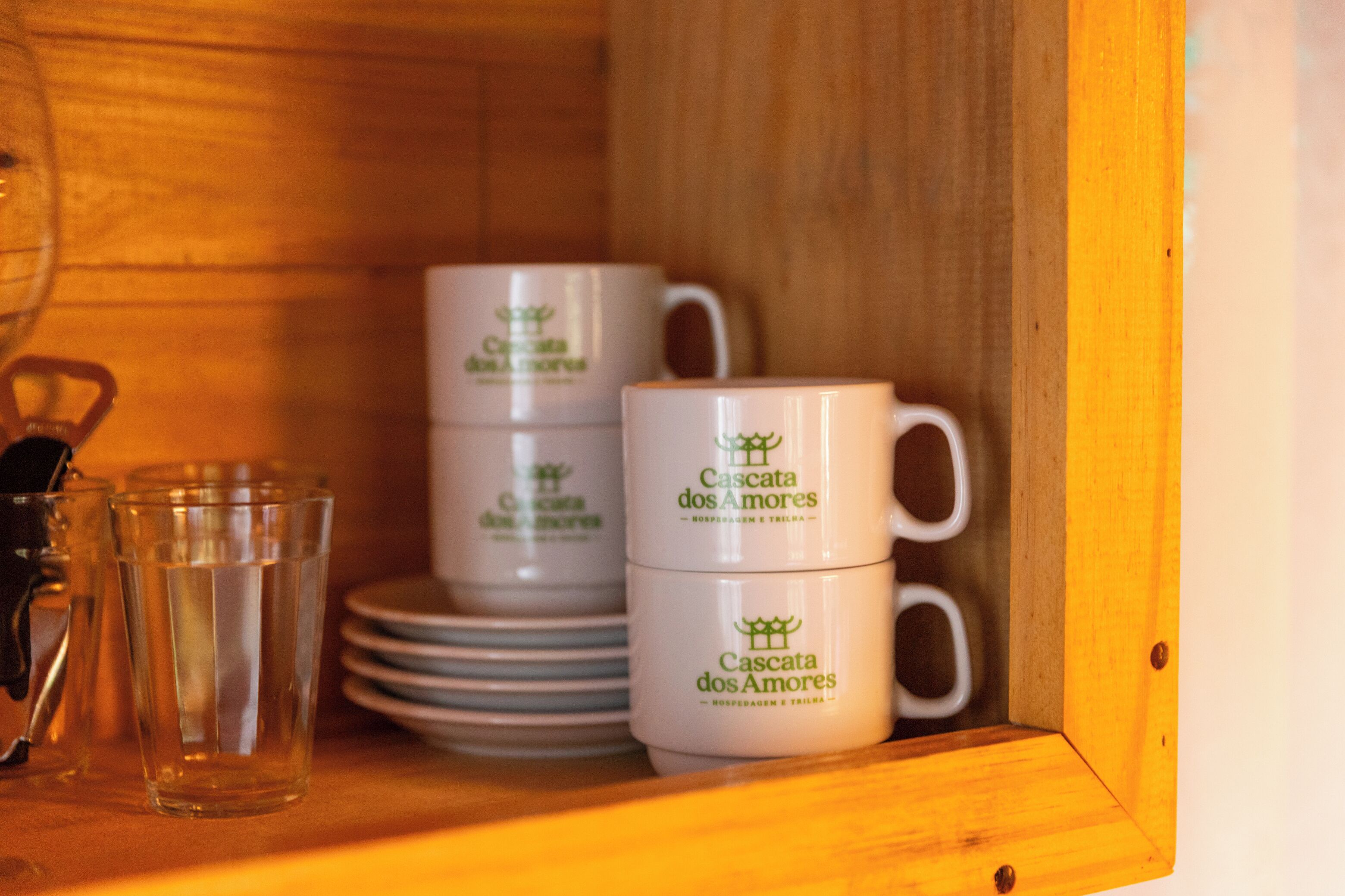 Una estantería de madera con tazas y vasos blancos.