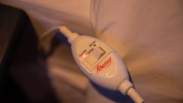 Una mesita de noche blanca con un dispositivo blanco encima, posiblemente médico o electrónico, con texto y botones visibles.