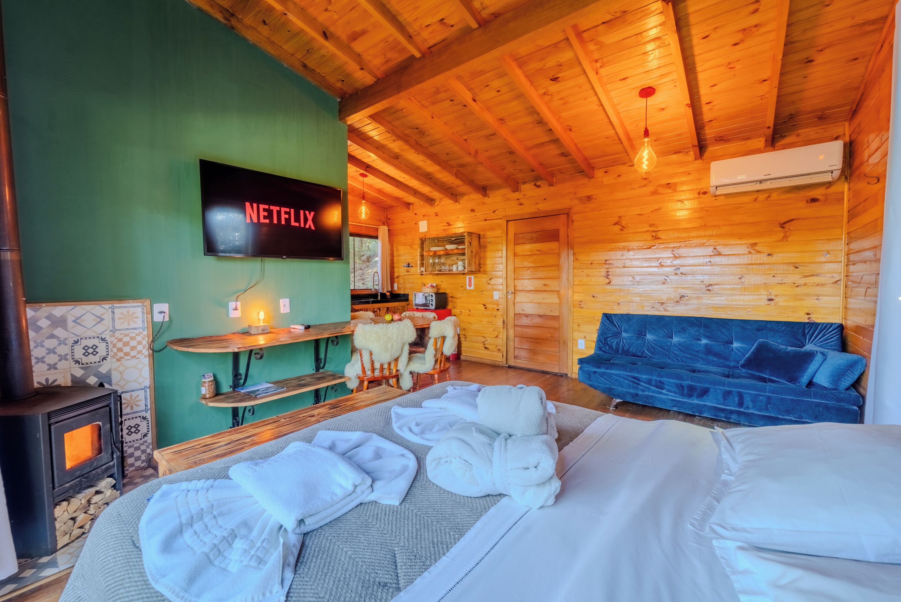 Una cabaña acogedora con interior de madera, chimenea, televisor y sofá.