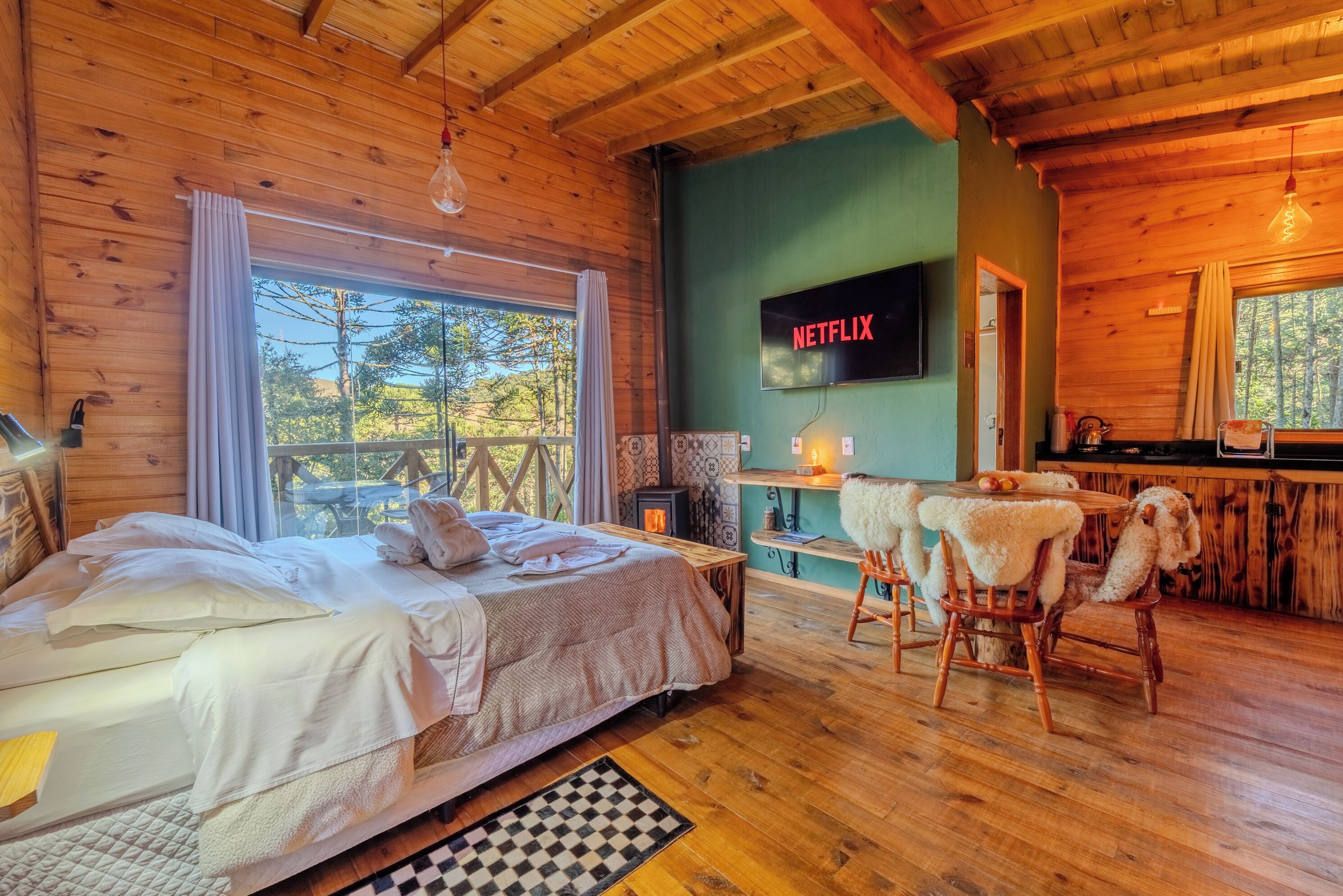 Accogliente camera da rifugio in legno con un letto, una TV a parete, un camino e vista sull'esterno.