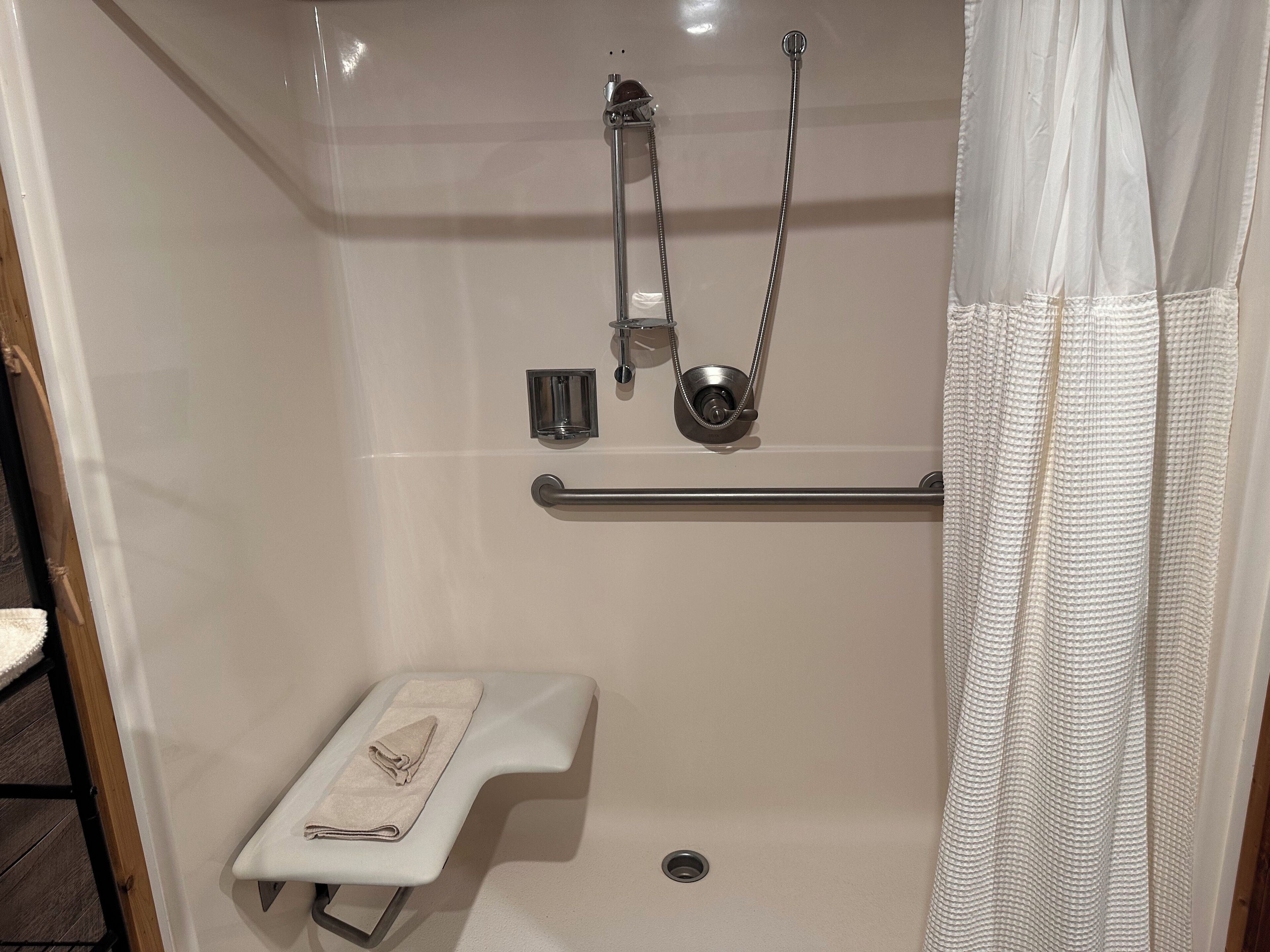 Un baño con ducha, inodoro y barra para toallas.