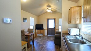 A kitchen with a microwave, sink, and wooden cabinets. - Red Leaf Cottages (Lake Village)