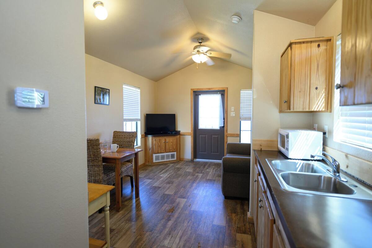 A kitchen with a microwave, sink, and wooden cabinets.