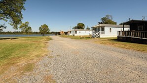A gravel path leading to a row of cabins by a lake. - Red Leaf Cottages (Lake Village)