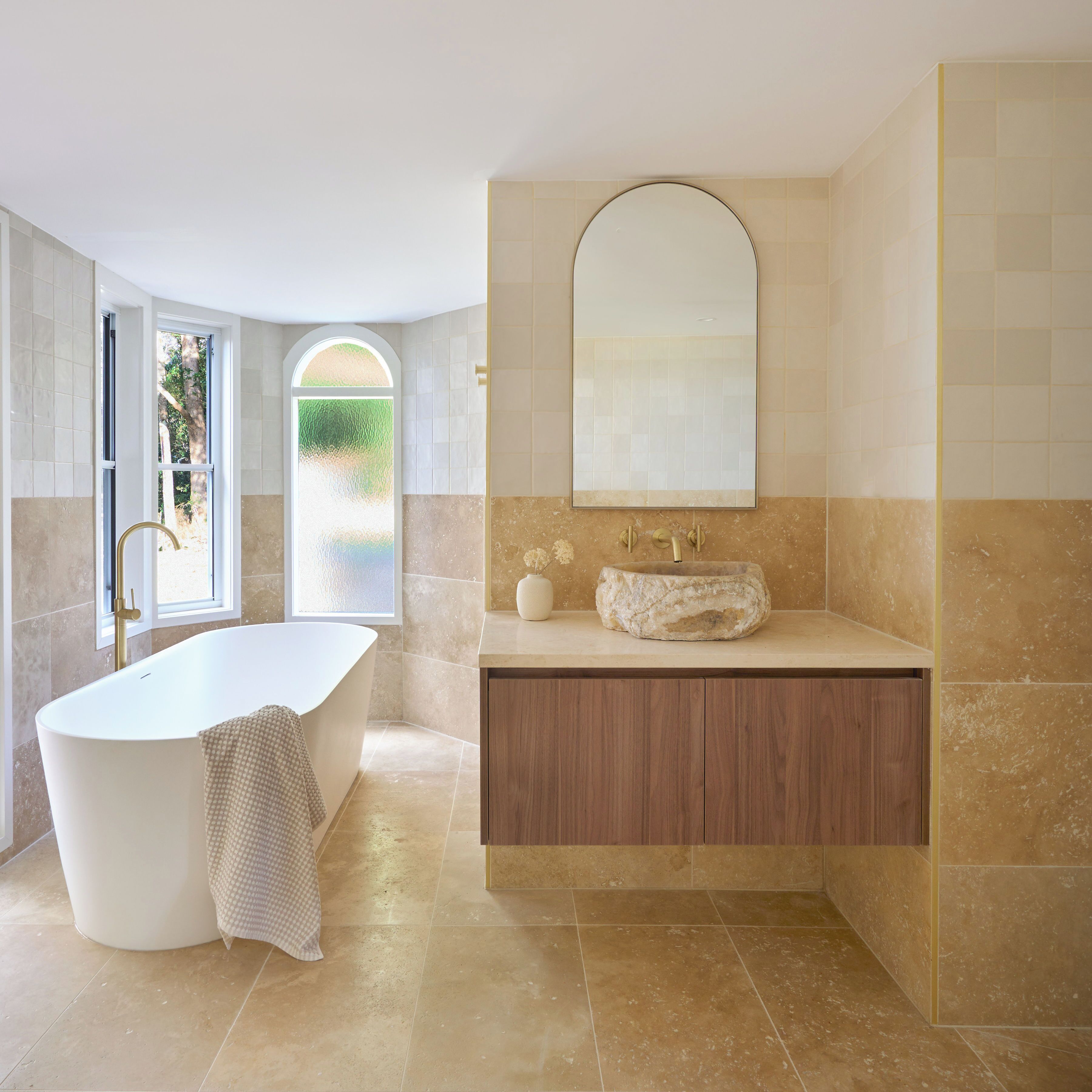 A modern bathroom with a freestanding bathtub, a wooden vanity, and a large mirror above the sink.