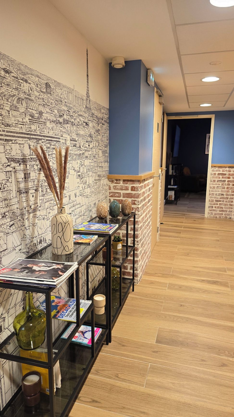 Un área de recepción con un mural en la pared, un mostrador de recepción con revistas y una pared de acento de ladrillo.