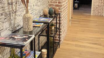 Un área de recepción con un mural en la pared, un mostrador de recepción con revistas y una pared de acento de ladrillo.