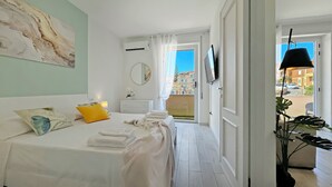 Hotellihuone, jossa on sänky, yöpöytä, peili, televisio ja näkymä ulos.
